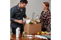 Image Man and woman unpacking box of food.